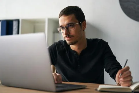 Young man working with computer, phone and tablet at the table while drinking Stock Photos
