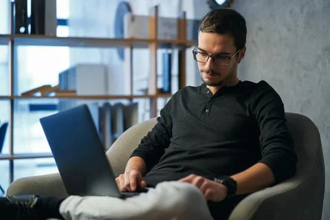 Young man working with computer, phone and tablet at the table while drinking Foto stock