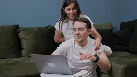 Young man that is working at the computer receiving a gift from his wife. Stock Footage 146807582