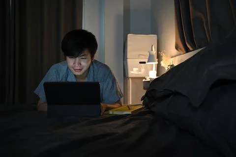 Young man working with computer tablet on his bed. Stock Photos