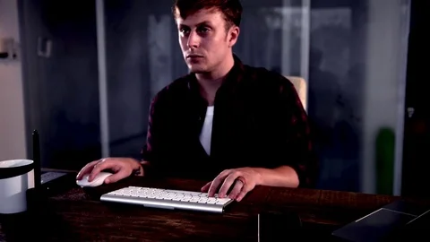 A young man working on a computer in their home. Video stock 83113707