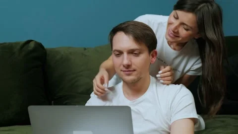 Young man that is working at the computer while his wife are kissing him Stock Footage 168529995