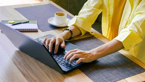 Young man working at a computer in a yellow shirt Stock Photos