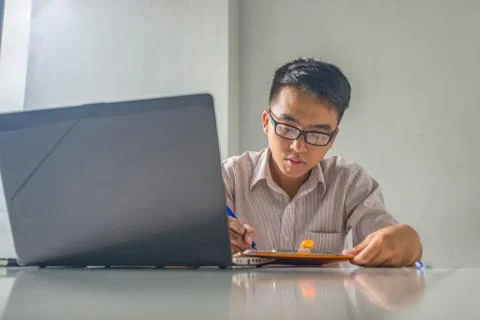 Young man working on financial document and laptop at workplace Stock Photos