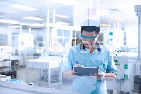 Young Man Working In Flexible Electronics Plant, Writing In File