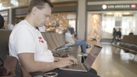 Young man working on his computer before his flight Stock Footage 116024772