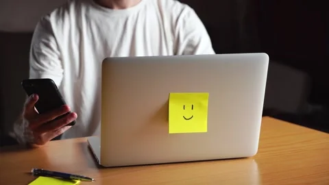 Young man is working on his laptop and checking notifications on his phone. Stock Footage 245548619