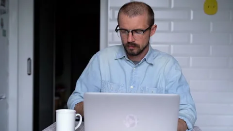 Young man is working from home and drinking from a cup. Stock Footage 135980970