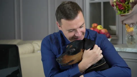 Young man is working from home with his computer in office and his dog distracts Stock Footage 167793763
