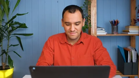A young man with working from home at the notebook in cozy room. Video stock 148237384