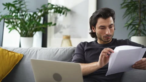 Young man working from home using laptop and browsing documents Stock Footage 149240867