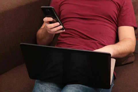 Young man working at home using laptop and smartphone Stock Photos