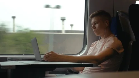 A young man is working on a laptop and listening to music in moving modern train Stock Footage 112432885
