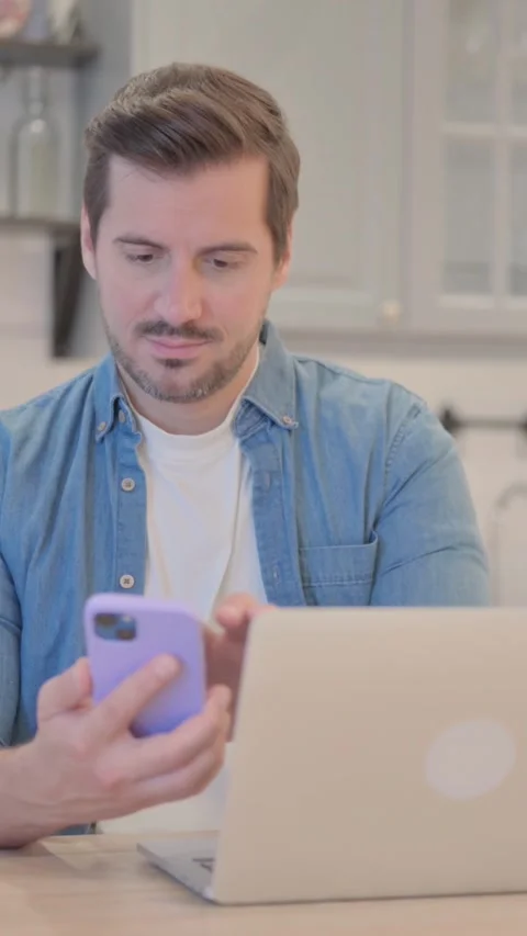 Young Man Working on Laptop and Using Smartphone, vertical video Vidéo 328565727