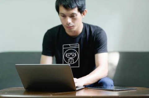 Young Man Working on Laptop with Chatbot Design T-Shirt Stockfoto's