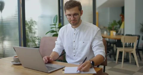 Young man working with laptop in coffee shop.Guy checking information and making Stock Footage 160920286
