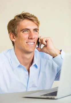 Young man working on laptop computer talking on phone Stock-Fotos