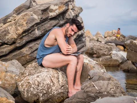 Young man working on laptop computer at beach Stock Photos