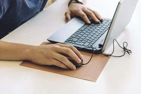 Young man working with laptop, hands on notebook computer and mouse. Focus on Stock Photos