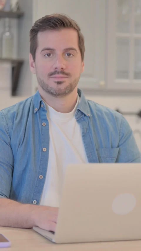 Young Man Working on Laptop Looking toward Camera, vertical video Video stock 328565766