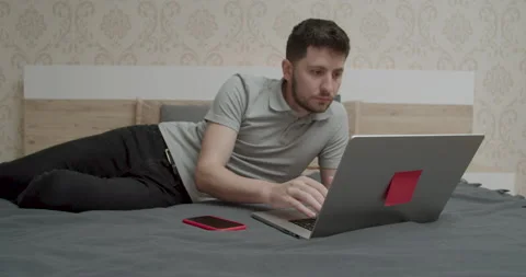 Young man working on a laptop lying in bed. Stock Footage 194422683