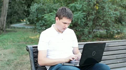 A young man working on a laptop in the park Stock Footage 19928194
