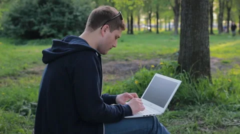 Young man working on laptop in the park Stock Footage 64481933