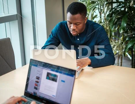 Young man working on a laptop in public library Stock-Fotos