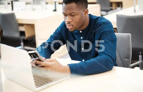 Young Man Working On A Laptop In Public Library