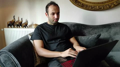 Young Man is Working at Laptop Sitting on Sofa Stock Footage 144080894