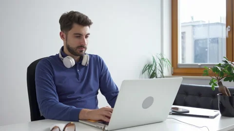 Young man working on laptop sitting at desk in small office Stock Footage 162467058