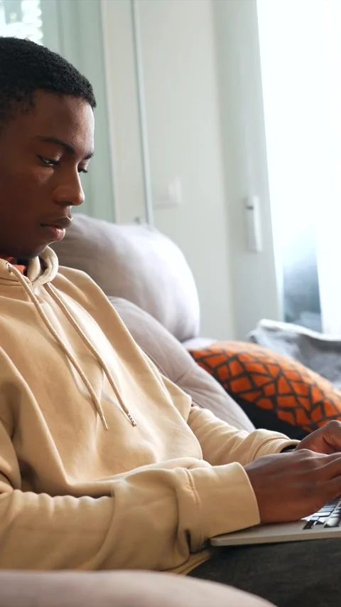 Young man working on laptop on sofa at home Stock Footage 307290478