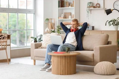 Young man working with laptop on sofa at home Stock Photos