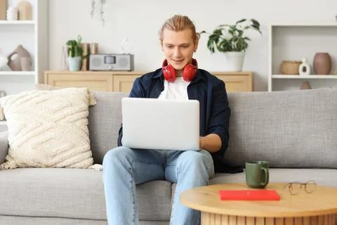 Young man working with laptop on sofa at home Stock Photos