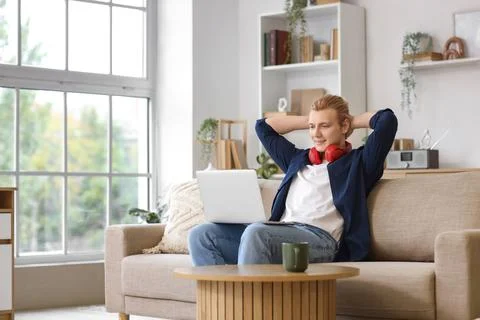 Young man working with laptop on sofa at home Stock Photos