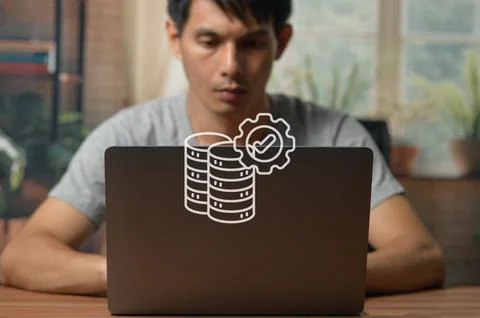 Young Man Working on Laptop with Technology Icon Overlay in Indoor Setting Stock Photos