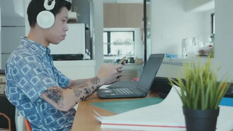 Young Man Working on Laptop While Listening to Music Stock Footage 314594156