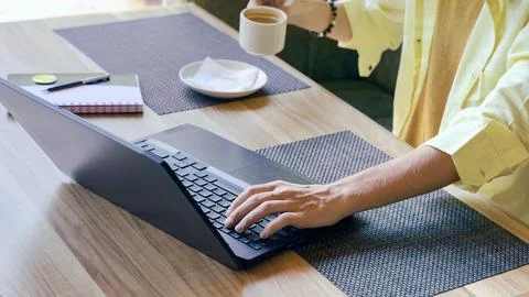 Young man working on a laptop while drinking coffee Stock Photos