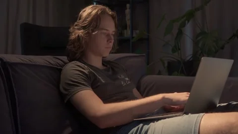 Young man working late on his laptop in a dark room, lit by the screen Video stock 310739261