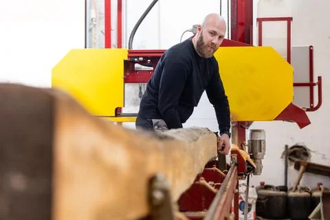 Young man working on the machine for processing the wood, huge wood cutter or 库存照片