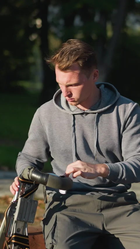 Young Man Working on Metallic Device Outdoors in Sunny Park Setting Stock Footage 310200619