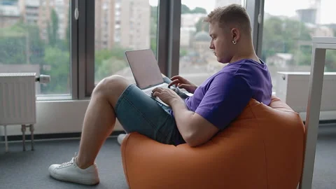Young man working in modern office sitting on the sandbag Stock Footage 111696360