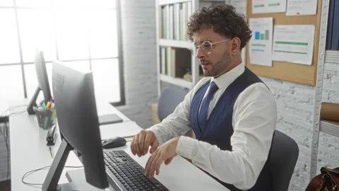 Young man working in modern office using computer wearing glasses and forma.. Stock Footage 296890834