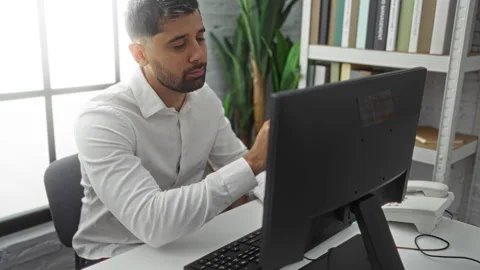 Young man working in a modern office setting, focused on a computer, dresse.. Stock Footage 303950628