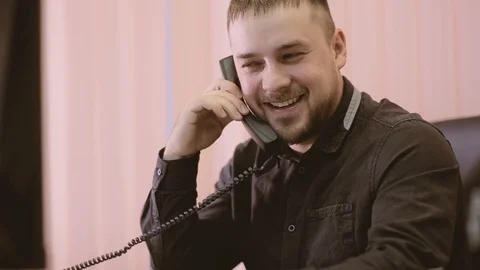 A young man is working in the office and talking on the phone. Stock Footage 89669481