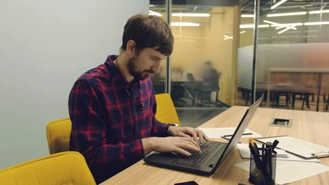 Young man working in the office on a laptop. Office worker sitting at the table Video stock 149056076