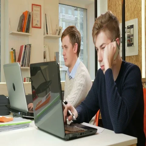 Young man working in the office of the laptops on the project. One is calling on Stock Footage 69524039
