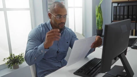 Young man working in an office, reading documents at a desk with a computer.. Stock Footage 283545145