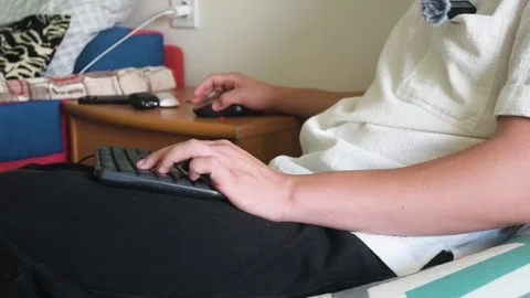 Young man working or playing games remotely with a keyboard and computer mouse Stock Footage 347652274