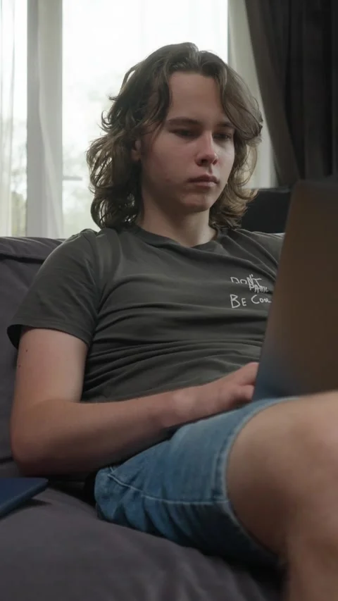 Young man working or studying on his laptop from home, sitting on a couch Stock Footage 310739258